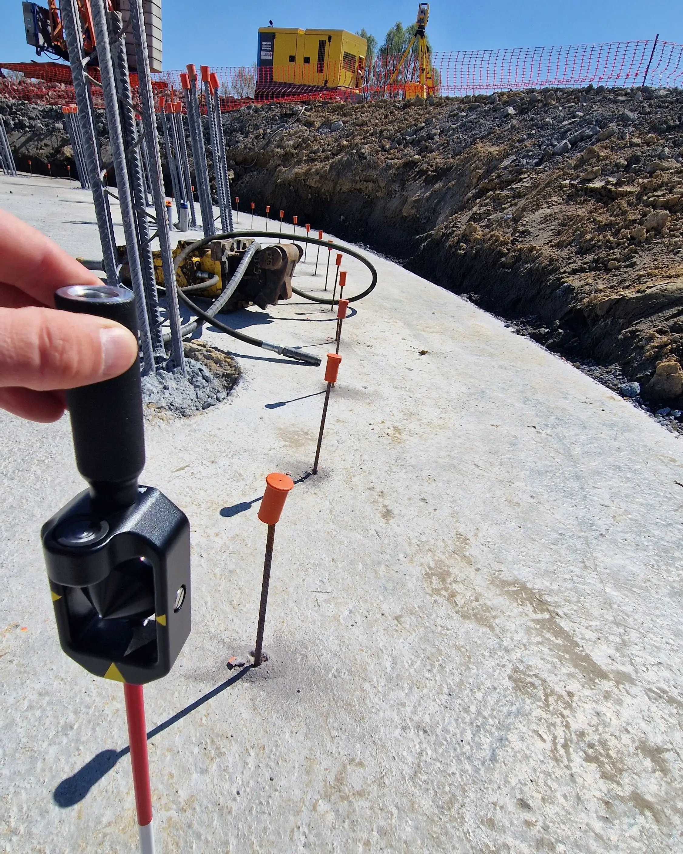 Prisme et jalons implantés sur une dalle de chantier