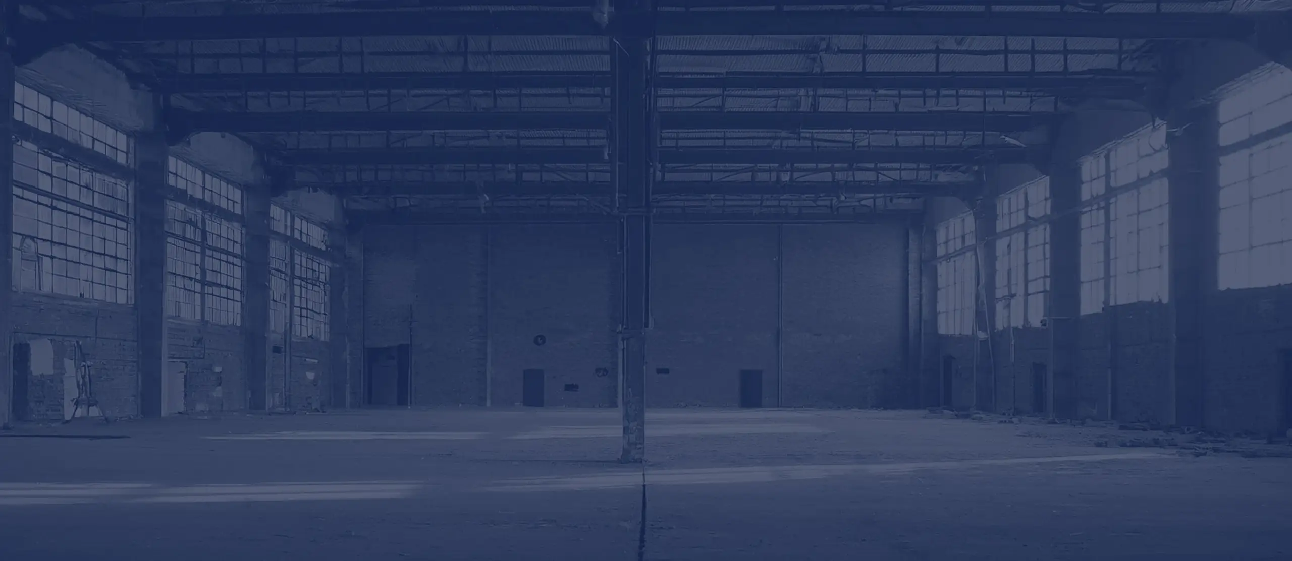 Halle industrielle vide, murs de brique, ossature métallique et grandes baies
